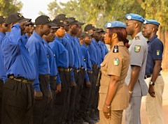 A group of uniformed officers standing in rows facing three officers.