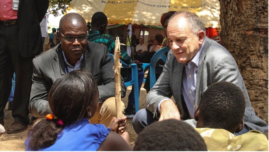 Two men talk to children in South Sudan