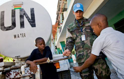 Ky Chung, un miembro del contingente boliviano de MINUSTAH abre un grifo de agua para un joven.