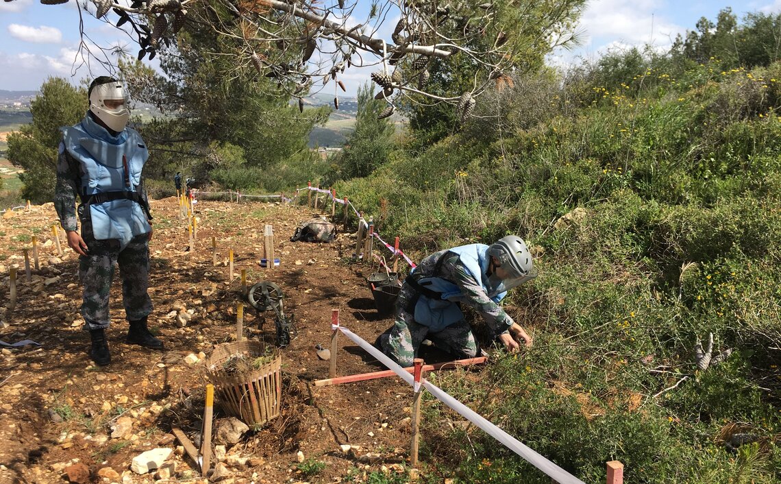 Deux soldats de la paix en tenue de protection examinent le sol sous des arbres