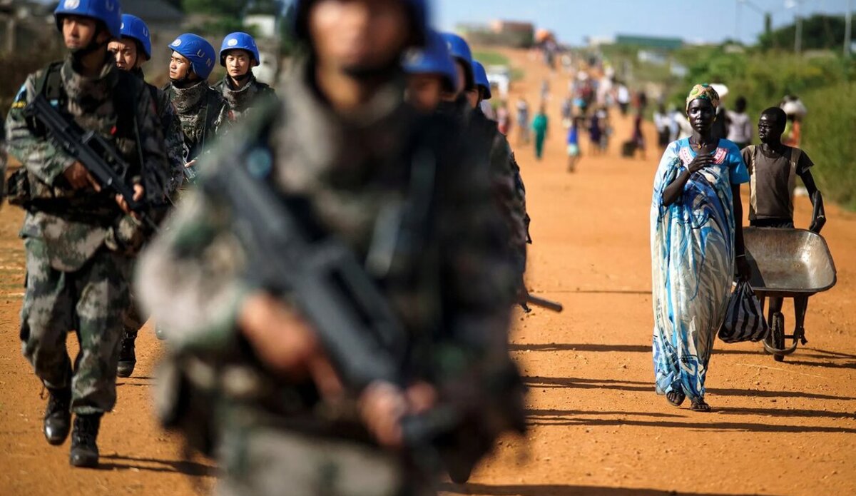 Peacekeepers patrol along a road where civilians are walking in South Sudan