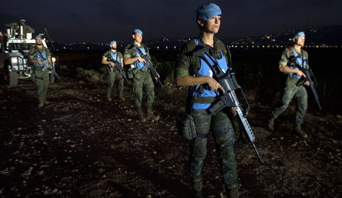 A group of armed UN peacekeepers patrol at night 