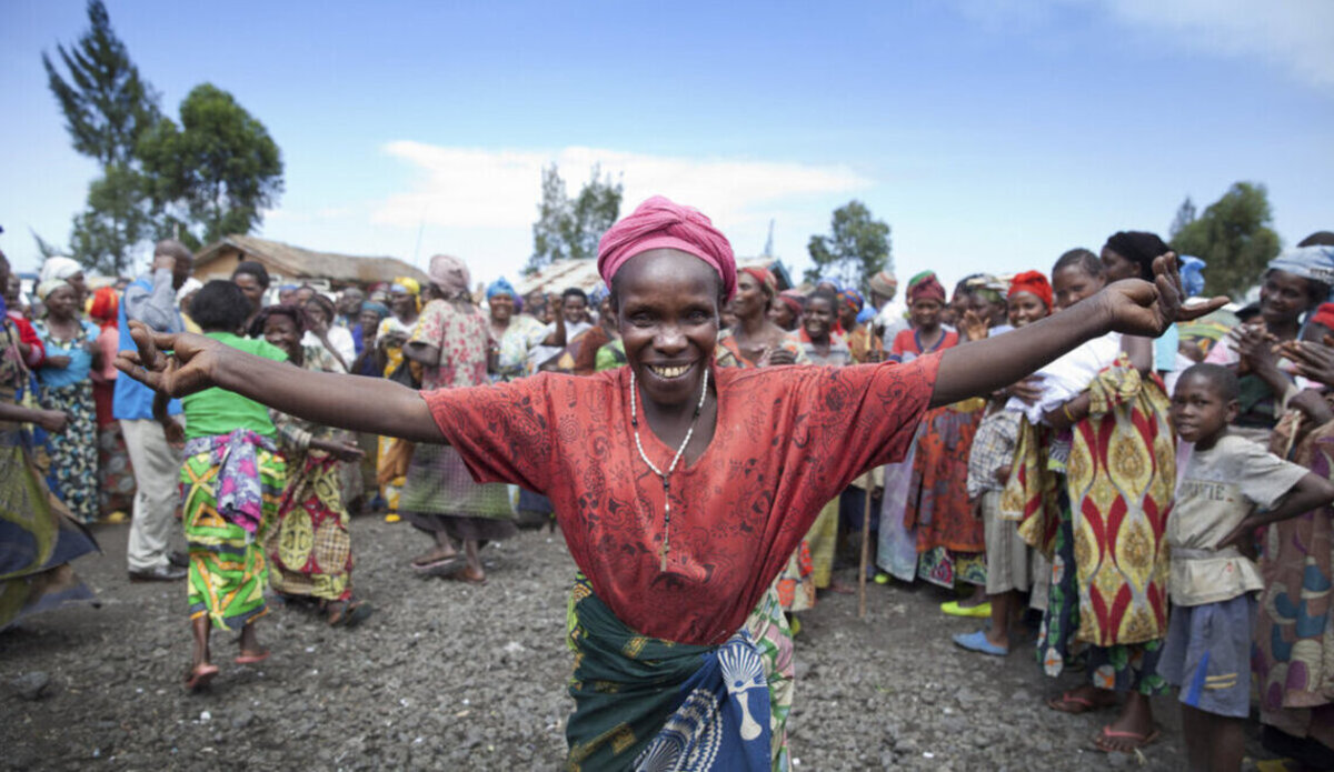 Une femme au milieu d'une foule tend les bras devant l'objectif de l'appareil photo