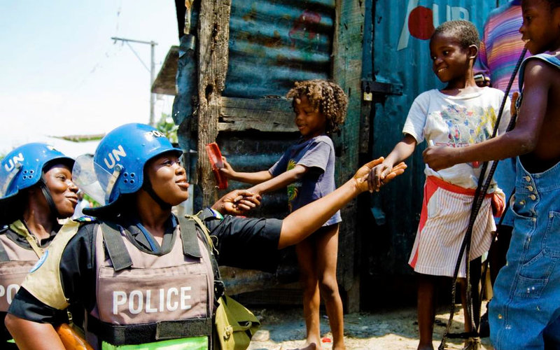 Los oficiales nigerianos de la FPU hablan con los niños mientras patrullan el barrio marginal de Martissant