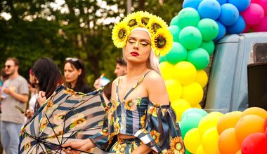 People march in a pride parade surrounded by colourful balloons